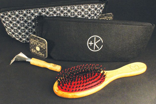 Two zippered pouches, a Cult and King Boar Bristle & Nylon Styling Brush | Brush Handle is 100% Bamboo from well-managed forests with a wooden handle and red cushion, and a small rake-like tool, all displayed on a dark background.