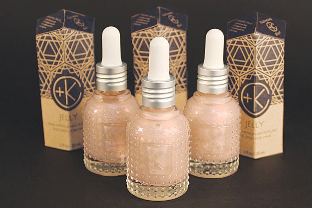 Three Cult and King JELLY glass dropper bottles, containing pink Himalayan salt infusion for hair, are displayed with geometric-patterned boxes on a black surface.