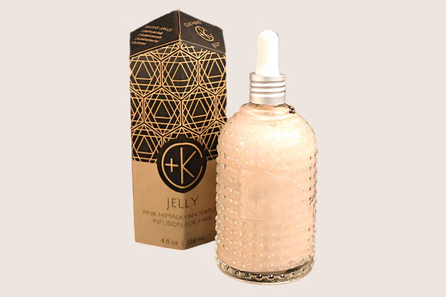 Cult and King's JELLY, a pink Himalayan salt infusion for hair, comes in a glass bottle with natural texture and a dropper. A box with geometric designs accompanies it, enhancing the presentation.