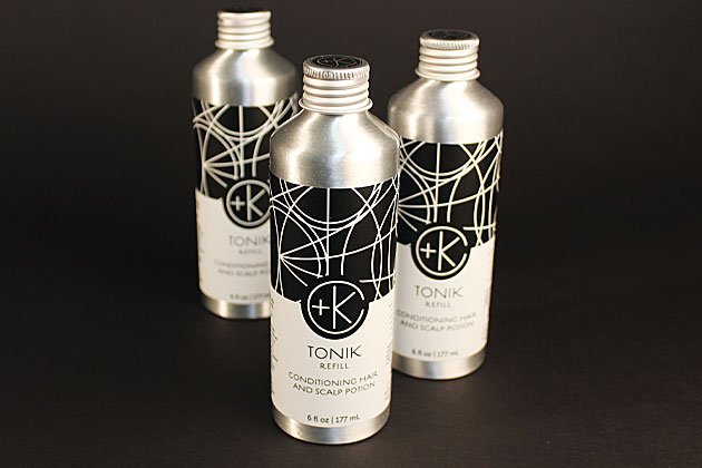 Three silver-toned bottles labeled "Cult and King TONIK | Conditioning Hair & Scalp Potion" are arranged on a dark surface. Each vegan, cruelty-free hair care bottle features a modern, abstract black and white design.