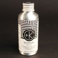 A 4 oz silver aluminum bottle labeled "CULT+KING SETSPRAY | NEW FORMULATION: Semi-Precious Tri-Phase Wonderworking Hairspray" with black and white geometric designs, stands against a black background, boasting organic ingredients for a botanically-infused hairspray that offers excellent heat protection from Cult and King.