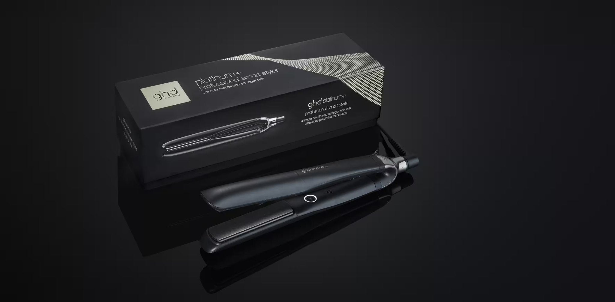 A black GHD PLATINUM+ STYLER - 1" FLAT IRON, designed for personalized results, is placed next to its packaging box against a dark background.
