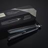 A black GHD PLATINUM+ STYLER - 1" FLAT IRON, designed for personalized results, is placed next to its packaging box against a dark background.