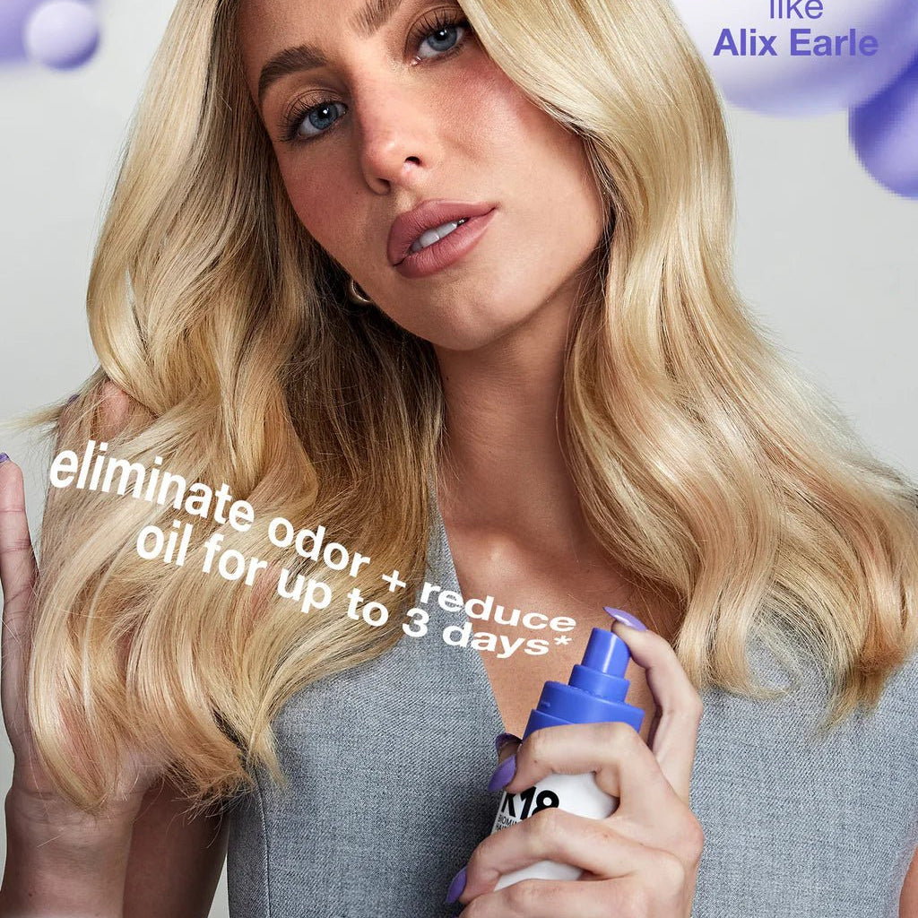 A person with long blonde hair holds a spray bottle of K18 AirWash Dry Shampoo by Simply Colour Hair Salon Studio & Online Store while looking at the camera. Text on image reads, "eliminate odor + reduce oil for up to 3 days*.