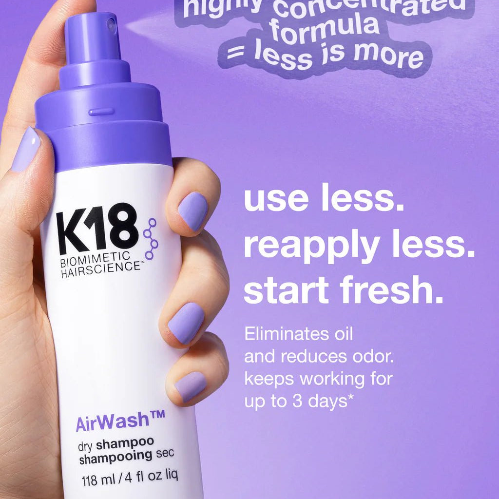 A hand holds a bottle of K18 AirWash Dry Shampoo by Simply Colour Hair Salon Studio & Online Store against a purple background. Text highlights its concentrated formula, powered by odorBIND biotechnology, suggesting to "use less, reapply less, start fresh" and that it works up to 3 days.