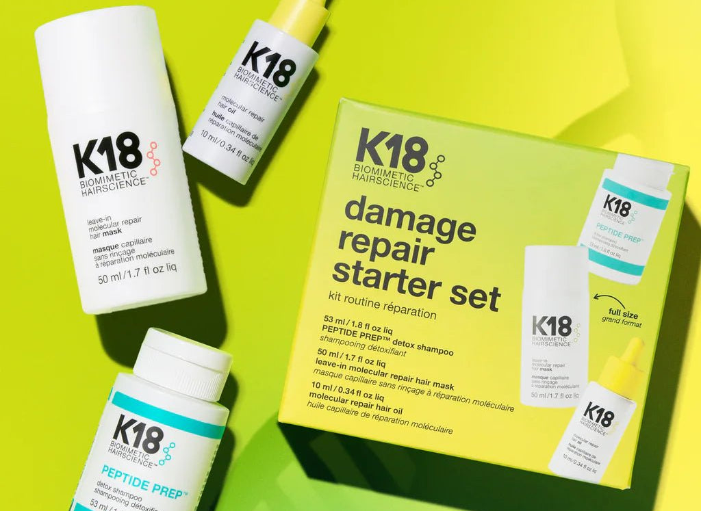 Image of K18 Hair Repair products against a gradient yellow-green background, featuring the K18 Damage Repair Starter Set, including a bottle of leave-in molecular repair hair mask, a bottle of peptide prep shampoo, and a bottle of hair oil. These vegan products harness the power of K18Peptide to reverse damage effectively.