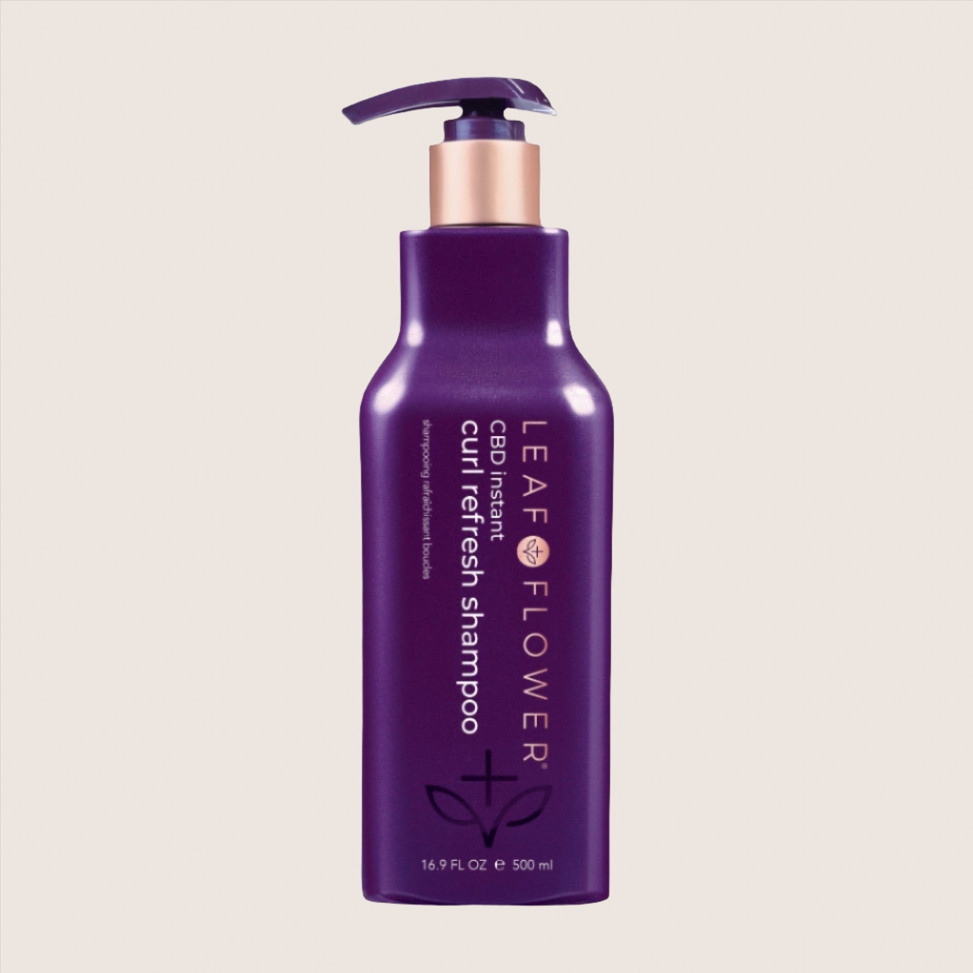 A purple bottle of Leaf and Flower Instant Curl Refresh Shampoo with a pump top, labeled "Leaf and Flower Instant Curl Refresh Shampoo," 16.9 FL OZ (500 ml). This color-safe formula gently removes build-up, leaving your curls hydrated and refreshed.