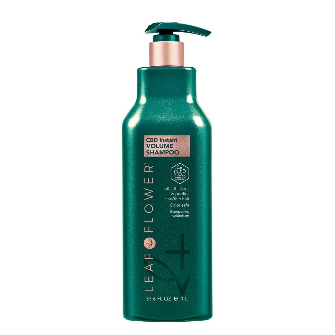 A green 33.8 fl oz bottle of LEAF and FLOWER Instant Volume Shampoo, plant-based and sulfate-free, with a pump dispenser. Labeled as lifting, thickening, and purifying for fuller hair.