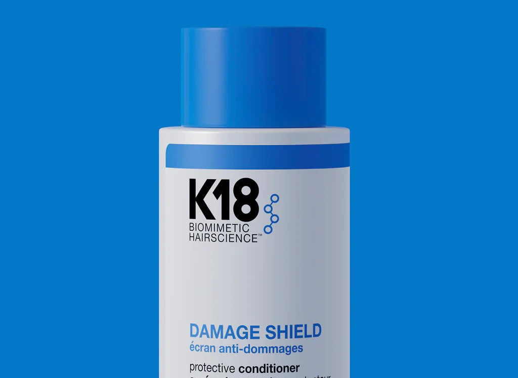Bottle of K18 Hair Repair K18 Damage Shield pH Protective Conditioner - Multiple Sizes, a nourishing conditioner for hair health, on a blue background.